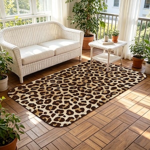 May include: A rectangular area rug with a leopard print pattern in shades of brown and tan. The rug is placed on a wooden deck, with a white wicker sofa and small table in the background. Potted plants add greenery.