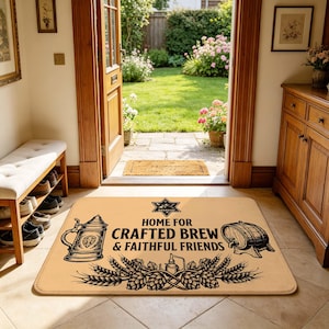 Puede incluir: Un felpudo rectangular de color tostado con un diseño gráfico negro de una jarra de cerveza, un barril de madera y espigas de trigo. El texto dice: HOME FOR CRAFTED BREW & FAITHFUL FRIENDS, con un emblema en forma de estrella sobre el texto.