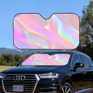 May include: A car sunshade with a vibrant, iridescent design in shades of pink, yellow, and blue. The sunshade is installed in the windshield of a black SUV, offering protection from the sun's rays. The design creates a colorful, shimmering effect.