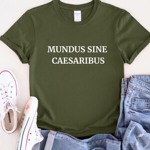 May include: A green t-shirt with white text that reads "MUNDUS SINE CAESARIBUS".