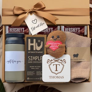 Peut inclure: Coffret cadeau avec ruban doré et étiquette "Gift with Love". Il contient des barres chocolatées Hershey's, un gobelet, du chocolat noir, une figurine de haricot crochetée, des chaussettes et un dessous de verre.
