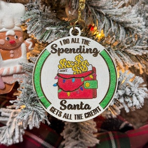 Adorno navideño hecho a mano con la frase "Yo gasto todo, Papá Noel se lleva todo el crédito" - Diseño divertido de billetera