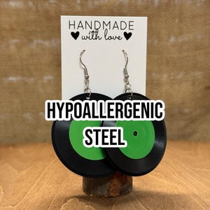 May include: A pair of black and green record earrings with hypoallergenic steel hooks. The earrings are handmade with love and feature a green center with a black outer ring.