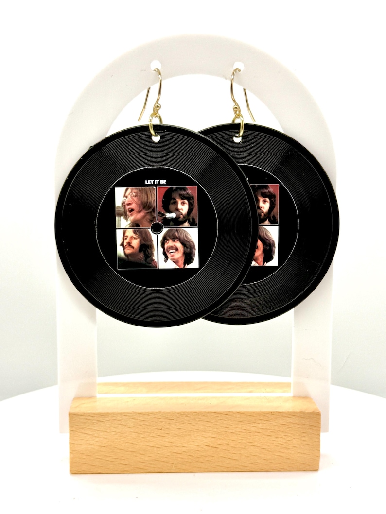 May include: A pair of black vinyl earrings featuring a Beatles album cover with the text "Let It Be".