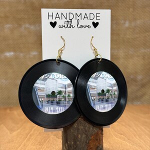 May include: A pair of black vinyl record earrings with a picture of the Palm Mall shopping center. The earrings are handmade and have gold hooks. The card behind the earrings says "Handmade with love."