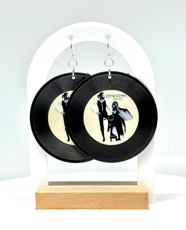 May include: A pair of black vinyl earrings featuring the Fleetwood Mac "Rumours" album cover. The earrings are hanging from silver hooks.