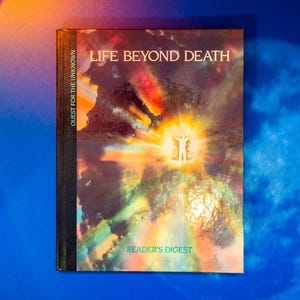 May include: A book titled "Life Beyond Death: Quest for the Unknown" by Reader's Digest. The cover features a colourful abstract image of a person standing in a bright light with a swirling background.