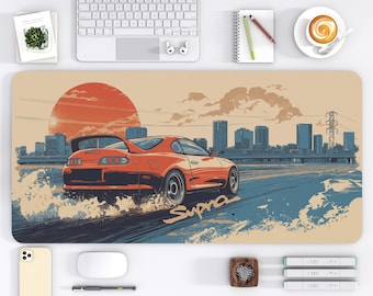 May include: Orange sports car desk mat with a cityscape and sunset design. The car is labeled "Supra" and is depicted on a road with water effects. The desk mat measures 16 x 32 inches.