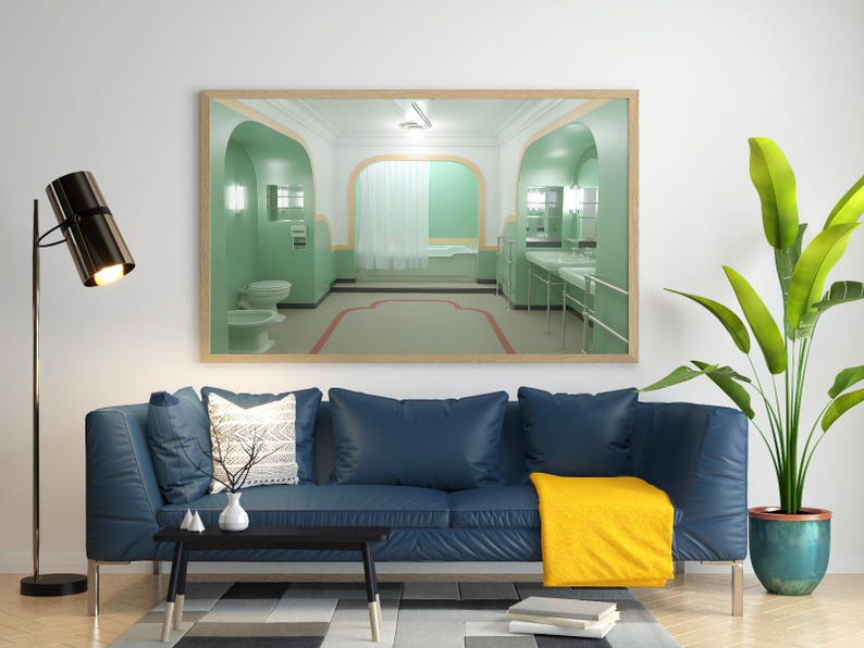 May include: A living room interior with a blue sofa, a coffee table, a floor lamp, and a framed picture of a green bathroom with a bathtub and sinks. A potted plant with green leaves is in the corner of the room.