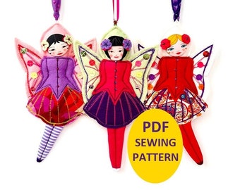 Può includere: Tre ornamenti di fata in feltro con ali di farfalla. Ogni fata ha un vestito e capelli di colore diverso. Le fate sono appese a una corda. Il testo "PDF SEWING PATTERN" è in un cerchio giallo.