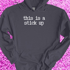 May include: A dark gray hoodie with a white print that says "this is a stick up".