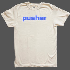 May include: A white t-shirt with a blue "pusher" graphic printed on the front.