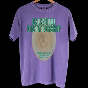 May include: Purple t-shirt with a faded graphic of a face in an oval with the text "CELESTIAL DICTATORSHIP" above it and "SPECIAL GUESTS TBA" below it.