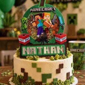 May include: A decorated birthday cake with a Minecraft theme. The cake is white with green and brown square accents and a green border. The cake topper features the number 7, the word "Minecraft", and character figures. The name "Nathan" is also displayed.