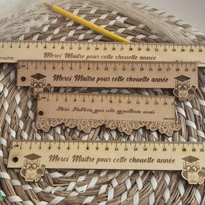Puede incluir: Cuatro reglas de madera con un diseño de búho y el texto "Merci Maitre pour cette chouette année" (Gracias Maestro por este gran año).