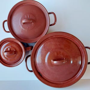 May include: A white ceramic mug with a black handle and the text "But First, Coffee" in a black, bold font. The mug is sitting on a wooden surface. The mug is 4 inches tall.