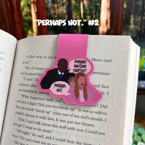 May include: A pink bookmark featuring a cartoon illustration of two people. The woman is holding a speech bubble that says "Perhaps Not." The man is holding a speech bubble that says "Perhaps Another Chapter?"