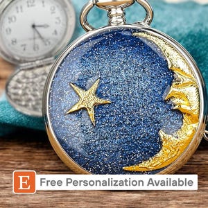 Peut inclure: Une montre de poche argentée avec un cadran bleu et or représentant une lune croissante et une étoile. La montre est munie d'une chaîne.
