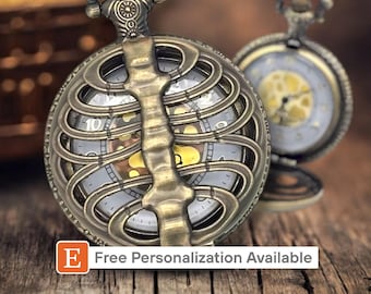 May include: A gold-toned pocket watch with a skeleton design. The watch face is visible through the skeleton design and has Roman numeral hour markers. The watch has a chain attached to it.