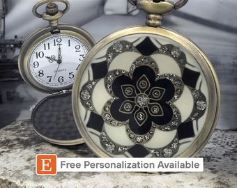 May include: A gold-toned pocket watch with a white face and black Roman numeral hour markers. The watch has a black and white patterned design with rhinestones on the back. The watch is open and the back is visible. The text "E Free Personalization Available" is visible at the bottom of the image.