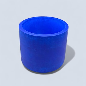 May include: A cylindrical, cobalt blue container. The object is a solid, smooth-sided cylinder with a hollow interior. The container is made of a solid material and is suitable for holding items. The object is set against a white background.