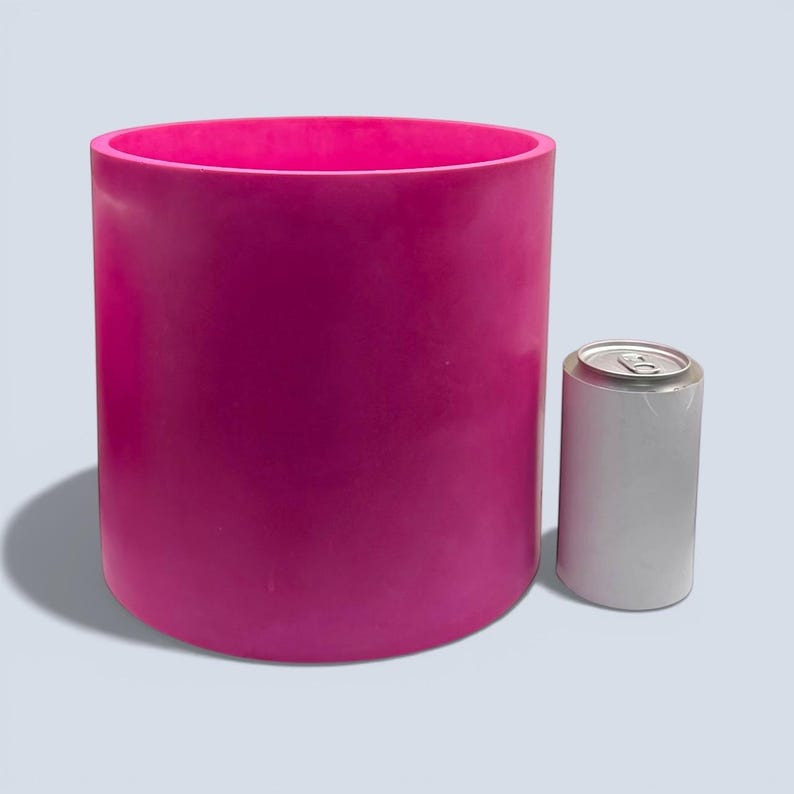 Large 23 cm handmade cylindrical plant pot in deep magenta pink, shown next to a white 330 ml drinks can for size comparison, smooth stone like finish, modern indoor planter for houseplants and statement decor.