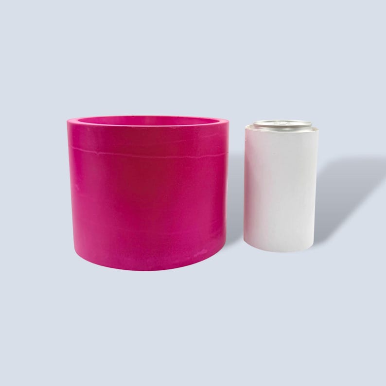 A vibrant magenta planter pot is next to a standard sized 330ml drinks can to give a comparison of size. The pot is slightly taller than the can and 3 times as wide. The bold colour is perfect for adding a pop of colour inside and the magenta contrasts beautifully with the green of plants leaves.