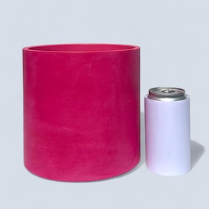 A large handmade vibrant magenta planter next to a white can to give an idea of scale. The pot is just under twice as tall and four times as wide. This large pot is suitable for housing medium to large sized indoor and outdoor plants.