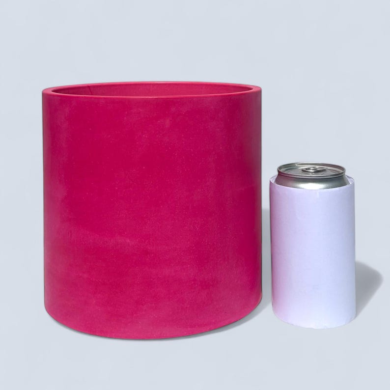 A large handmade vibrant magenta planter next to a white can to give an idea of scale. The pot is just under twice as tall and four times as wide. This large pot is suitable for housing medium to large sized indoor and outdoor plants.