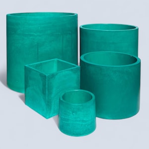 May include: A collection of five teal-colored cylindrical and square planters. The planters vary in size, with the largest being a tall cylinder. The surfaces have a marbled texture, adding visual interest. These decorative planters are suitable for indoor or outdoor use.
