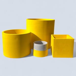 May include: Four yellow plant pots in different shapes and sizes. The set includes a cylindrical pot, a tall cylindrical pot, a small cylindrical pot with a grey band, and a square pot.