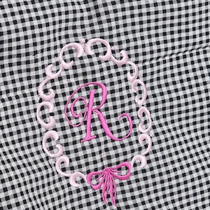 May include: Black and white gingham tote bag with a pink embroidered initial "R" inside a decorative frame. A pink bow is embroidered below the initial. The bag has black handles and a zipper closure.
