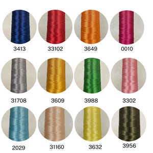 May include: A collection of twelve spools of thread in various colors, including blue, red, orange, pink, gray, gold, green, and brown. Each spool is labeled with a unique number. The threads appear to be smooth and shiny, suitable for sewing or embroidery projects.