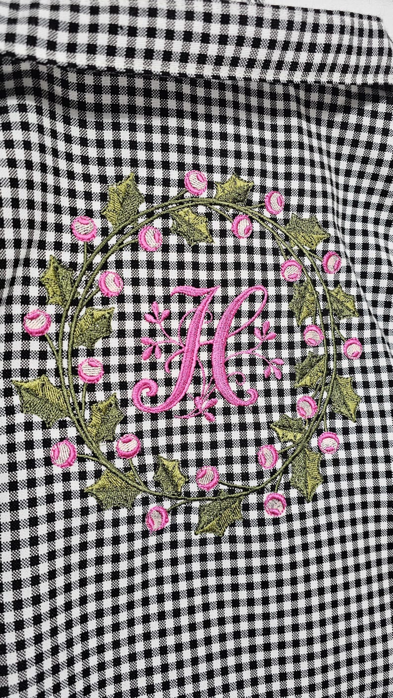 May include: Black and white gingham fabric with an embroidered wreath of green leaves and pink flowers. A large pink letter "K" is centered within the wreath, creating a personalized design.