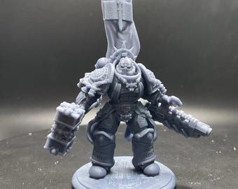 May include: A gray, 3D-printed miniature figure of a heavily armored warrior, standing on a circular base. The figure is equipped with a large hammer, a gun, and a banner. The armor is detailed with intricate designs.