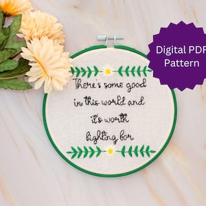 May include: A white embroidery hoop with green embroidery floss and a quote that reads "There's some good in this world and it's worth fighting for".