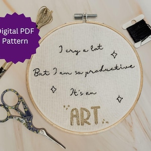 Op de afbeelding: Een borduurring met de tekst "I cry a lot but I am so productive. It's an ART." is omgeven door borduurgaren, een schaar en draad. Een paarse badge leest "Digital PDF Pattern".