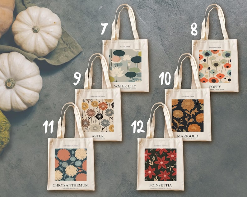 May include: A collection of cream-colored tote bags with various floral designs. Each bag features a different flower illustration, including water lilies, poppies, asters, marigolds, chrysanthemums, and poinsettias. The bags have cream-colored handles and the names of the flowers are printed on the bags.