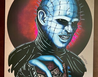 May include: A blue and black illustration of a character with a head covered in pins holding a box with a red and black design. The character has a sinister smile and is surrounded by black liquid.