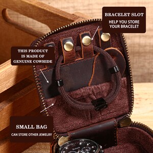 May include: A brown leather jewelry travel case with a zipper closure. The case has a bracelet slot and a small bag to store other jewelry. The text "THIS PRODUCT IS MADE OF GENUINE COWHIDE" is visible. A brown bracelet is inside the case.