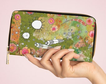 May include: A green zippered wallet with a colorful abstract design featuring flowers, feathers, and circles. The wallet is held in a hand.