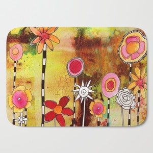 May include: A colorful bath mat with a whimsical design featuring a variety of flowers in shades of pink, red, orange, and yellow. The flowers are drawn in a cartoon style with black outlines and are set against a textured brown background.