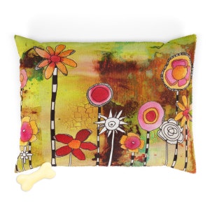 May include: A colorful dog bed with a whimsical floral design. The bed features a variety of flowers in shades of pink, red, yellow, and white, with black outlines. The background is a textured green and brown.