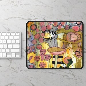 May include: A rectangular mousepad with a black border featuring a colorful abstract design. The artwork includes various shapes, faces, and organic forms in shades of yellow, pink, and green. A white keyboard is visible in the background.