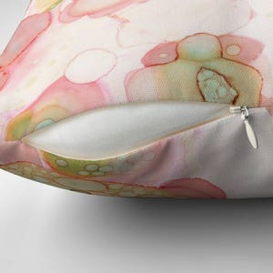 May include: Abstract pillow featuring a watercolor design with pink, green, and yellow colors. The design resembles a pattern of overlapping circles.
