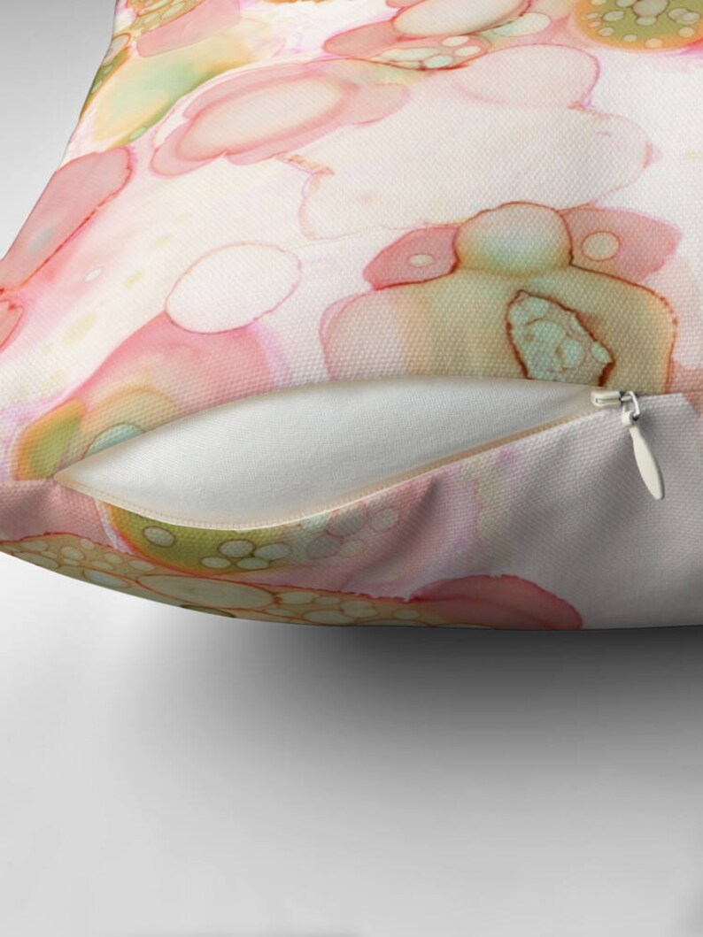 May include: Abstract pillow featuring a watercolor design with pink, green, and yellow colors. The design resembles a pattern of overlapping circles.