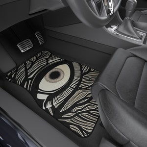 May include: Black car floor mat with a white and gray eye graphic design.
