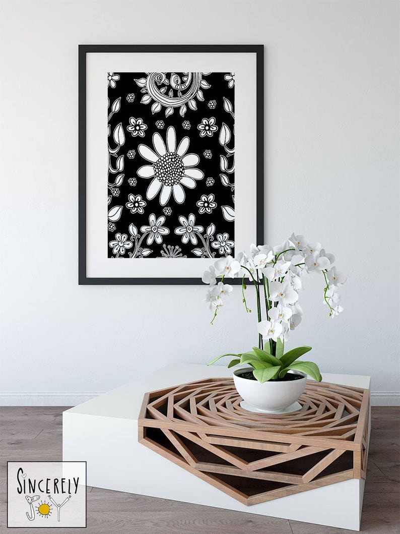 Puede incluir: Una obra de arte enmarcada con estampado floral en blanco y negro, una planta de orqu&iacute;dea blanca en una maceta blanca sobre una mesa de caf&eacute; blanca con un dise&ntilde;o geom&eacute;trico de madera.