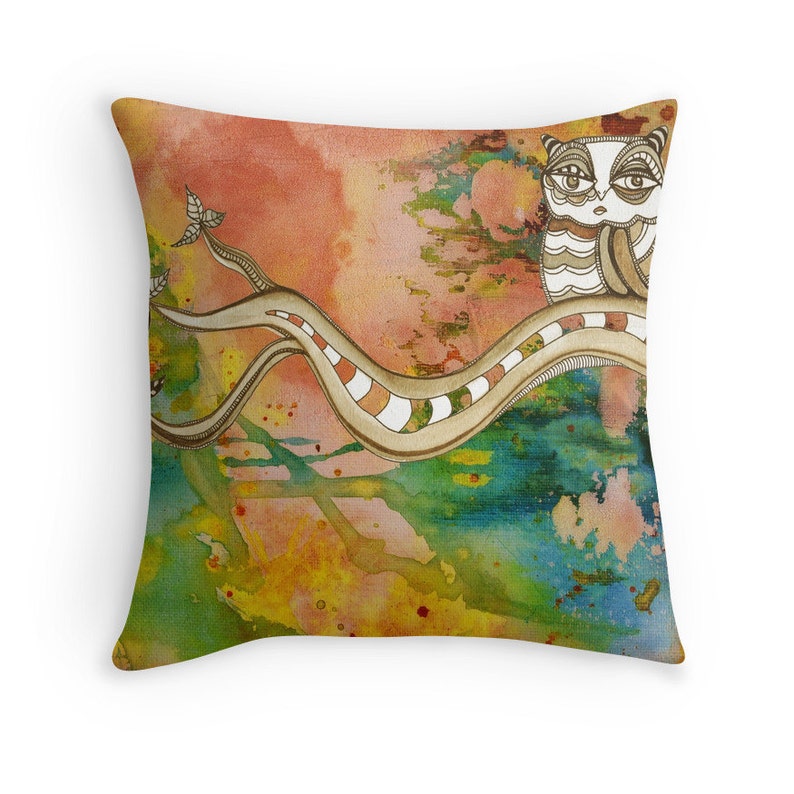 May include: A watercolour pillow featuring a stylised owl perched on a branch with a swirling, abstract background in shades of orange, yellow, green, and blue.