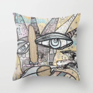 May include: A colorful abstract throw pillow with a design featuring multiple eyes and geometric shapes. The background is a mix of yellow, blue, and pink.